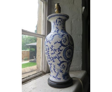 A hand painted pottery lamp base with a blue trailing design 