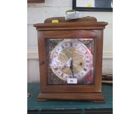 An oak cased mantel clock, retailed by Ridgeway, the caddy top over a brass dial and silvered chapter, the three train moveme