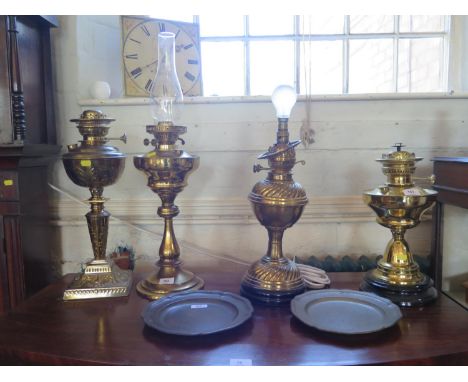 An Edwardian brass oil lamp, with repousse foliate decoration, tapering stem and square base, 48 cm high, three other brass o