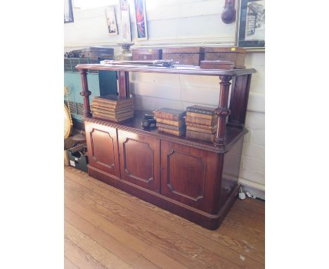 A Victorian mahogany buffet, the two tier top with fluted cabochon supports over three panelled doors (one enclosing a bottle