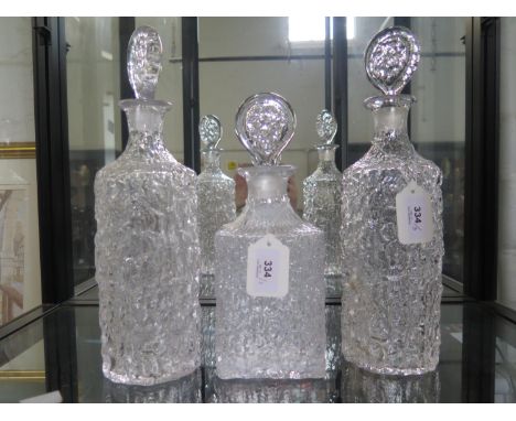A pair of Whitefriars clear glass bark effect cylindrical decanters and stoppers, 34 cm high, and a square decanter and stopp