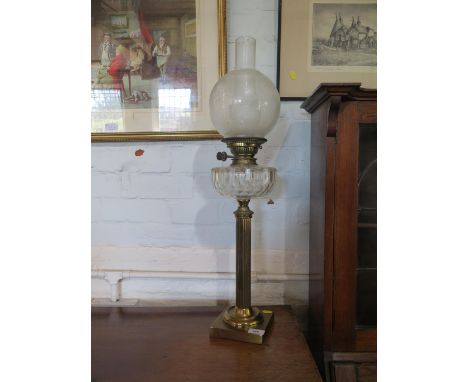 A brass column oil lamp, with facetted glass reservoir and fluted stem with square base, 63 cm high 