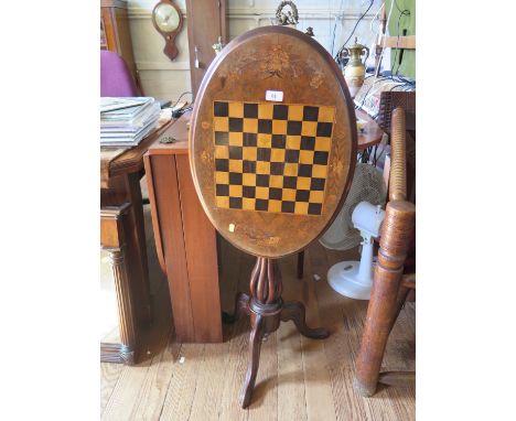 A Victorian inlaid walnut tripod games table, the oval top inlaid with a chequerboard and flowers on a reeded and open balust