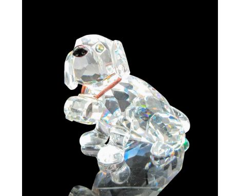 Clear faceted figural with tawny eyes, black nose, and elastic collar holding the cask. Swarovski backstamp. This item has it