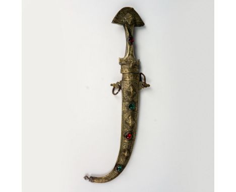 An exotic North African tribal Koummya dagger, showcasing intricately engraved brass and silver-tone metal fittings adorned w