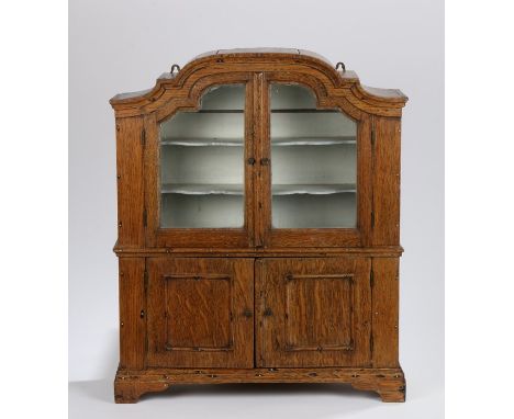 19th Century oak miniature cabinet, the arched plinth top above a pair of glazed doors enclosing shelves and a pair of cupboa