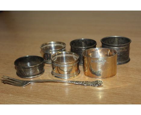 Six silver napkin rings, silver pickle fork, various dates and makers, 4.4oz
