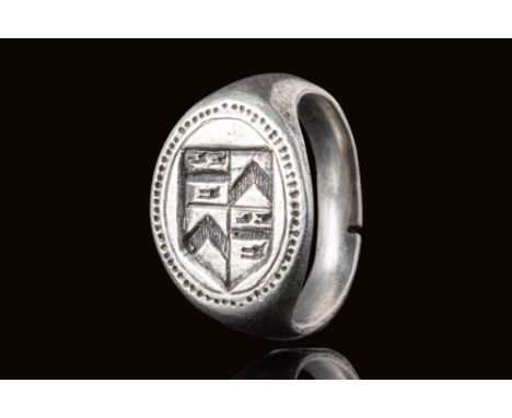 Ca. AD 1200 - 1400.A silver ring with an oval bezel engraved with a heraldic shield divided into four quadrants. Two quadrant