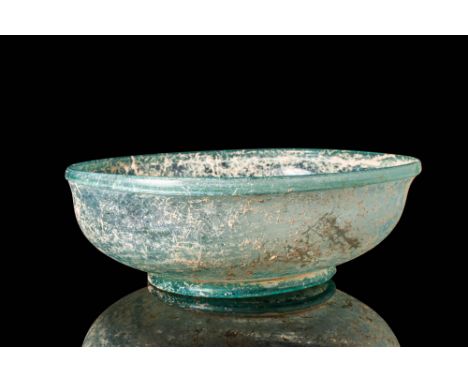 Ca. 100 BC - AD 100. A translucent green glass bowl with a wide, rounded body that flares gently towards the opening with a t