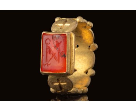 Ca. AD 600.A rectangular red carnelian intaglio engraved with a large monogram, framed by a raised gold border. It is set wit