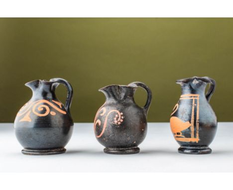 Ca. 350 - 280 BC. A group of three terracotta Xenon ware oinochoai, each with a black-glazed globular body, a trefoil mouth, 