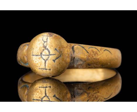 Ca. 600 AD.A gold ring with a broad, rounded hoop that slightly tapers towards the back. The circular bezel is slightly conve
