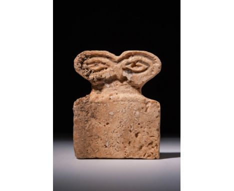 Ca. 3700 - 3500 BC. A stone eye idol featuring a rectangular body with a flat base and straight sides. The figure is topped w