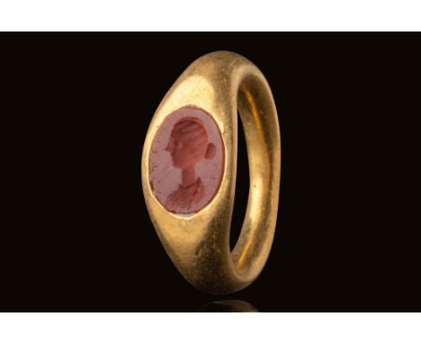 Ca. AD 100 - 200.A gold ring with a rounded hoop that broadens at the shoulders, forming an integrated bezel set with an oval