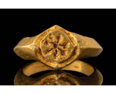 Ca. AD 1200 - 1300. A gold ring with a broad, slightly carinated hoop that thickens towards the bezel. Its roughly circular f