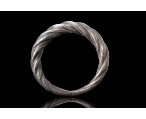 Ca. AD 800 - 1000. A silver ring with a twisted pattern. The median section is slightly expanded, where the twisting is most 