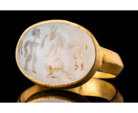 Ca. AD 200. An oval chalcedony intaglio engraved with a standing male figure on the left, shown in profile with a forward-lea