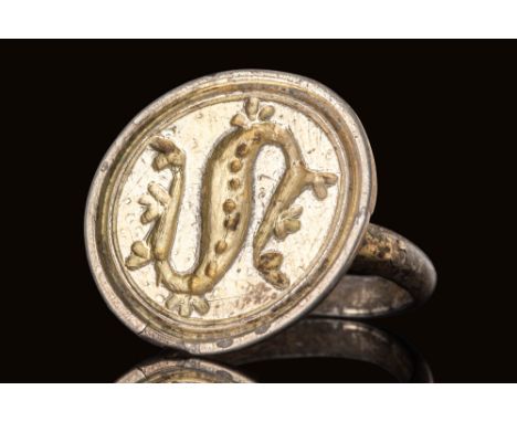 Ca. AD 1000 - 1100.A silver-gilt ring with a broad circular bezel depicting dragon Fafnir. A raised border encircles the beas