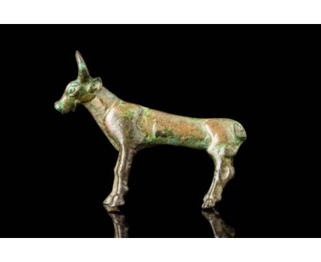 Ca. 800 - 600 BC. A bronze statuette of a bull standing on four slender legs. The head is defined by a broad muzzle, rounded 