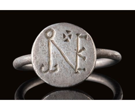 Ca. AD 500 - 600.A silver ring with a flat circular bezel engraved with a monogram composed of intersecting elements. A small
