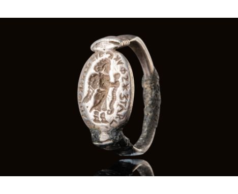 Ca. 400 BC.A silver ring with an oval-shaped bezel engraved with a depiction of a winged god in profile, grasping a snake in 