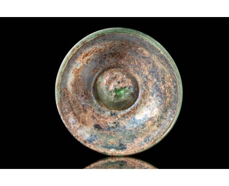 Ca. AD 100 - 200. A pale green glass bowl with a shallow, rounded body that expands towards a wide, everted rim. It rests on 