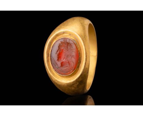 Ca. AD 50 - 300. A gold ring with a rounded hoop that expands towards an oval bezel set with a carnelian intaglio engraved wi