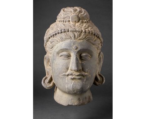Ca. AD 200 - 400. A carved stone head of Bodhisattva. The serene face depicts deep set almond eyes, with the urna, and lobed 