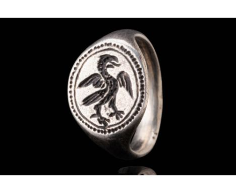 Ca. AD 1400 - 1600. A silver ring with a broad bezel engraved with a depiction of a griffon standing with outstretched wings 