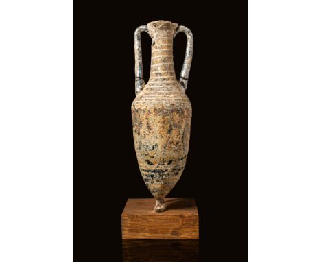 Ca. 300 - 100 BC. A core-formed glass amphoriskos with an elongated, tapering body ending in a small knob-like base. The surf