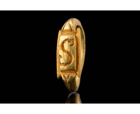Ca. AD 800 - 1100. A gold ring with a rectangular bezel featuring a central incised curvilinear motif with fluid lines. Two a