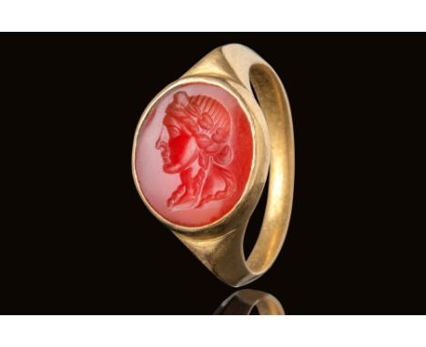 Ca. Late 2nd century AD.A carnelian intaglio engraved with a female portrait in profile, facing left. The elaborate hairstyle