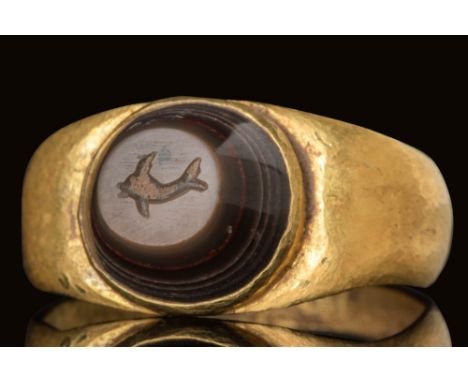 Ca. AD 100 - 300.A dark agate convex intaglio depicting a dolphin in profile, its body curving with a raised dorsal fin and a