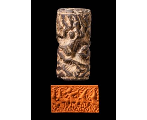 Ca. Mid to late 3rd millennium BC. A dark stone (gabbro?) cylinder seal depicting a complex composition with gazelles, birds,