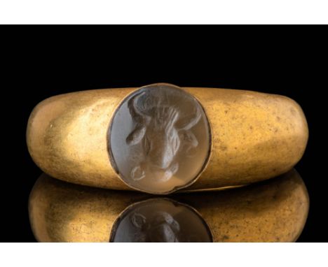 Ca. AD 200 - 600. A gold ring with a rounded hoop that thickens towards the bezel, set with a circular intaglio engraved with