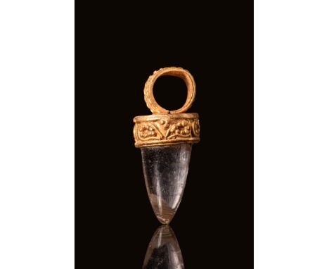 Ca. 300 BC. A gold pendant with a tooth-shaped rock crystal set within an ornate gold cap. The rock crystal is smoothly polis
