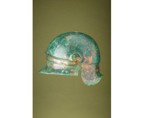Ca. 300 BC.A very rare bronze helmet with a rounded skull and a slightly flaring brim extending outward along the front and t