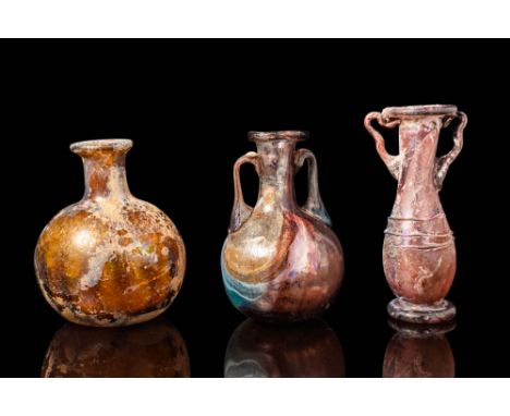 Ca. AD 100 - 500. A group of three glass vessels. The first on the left is a bottle with a globular body and a short cylindri