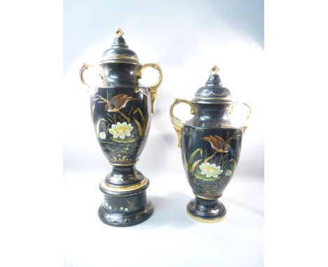 PAIR OF LATE VICTORIAN/EDWARDIAN CERAMIC URNS IN BLACK WITH GILDED DECORATION, PAINTED BIRD AND POND SCENE TO THE FRONT (HEIG