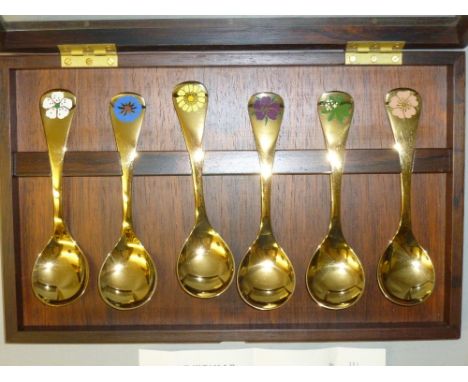 SET OF SIX GEORG JENSEN GILT WHITE METAL AND ENAMEL FLOWER SPOONS FOR 1976 WITH DIFFERENT FLOWER DESIGN ON EACH TERMINAL (L: 