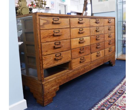 A vintage oak haberdashery cabinet fitted with 19 drawers (one missing), length 178cm, height 92cm, depth 58cm.