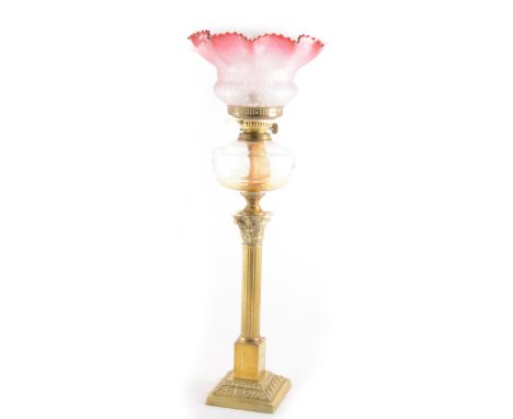 A brass Corinthian column oil lamp, clear glass reservoir, tinted shade, with chimney 75cm.