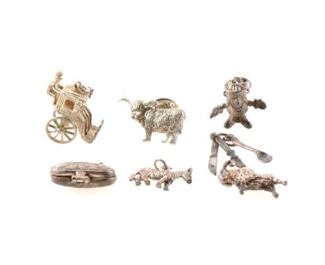 A collection of silver charms, including a cuckoo clock, church, carriage, house and hedgehog.