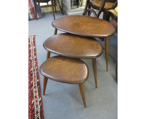A vintage nest of three Ercol dark stained elm pebble shaped tables 