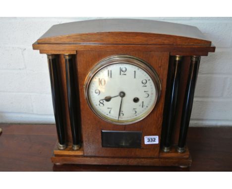 An oak cased 8 day striking mantle clock with ebonised turned pillars, glass panel showing pendulum - Height 33cm - working i