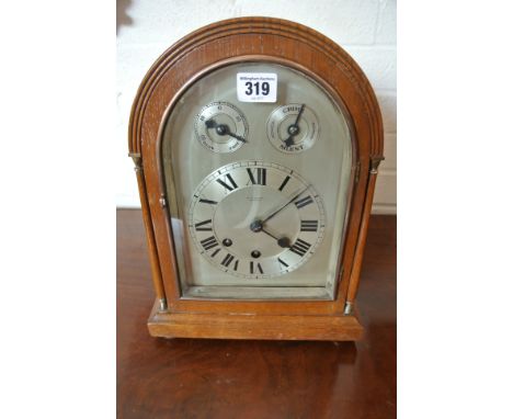 An early 20th century oak case bracket clock with Westminster chimes - the arched silvered dial with fast/slow chime/silent d