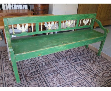 A 19th century bench, with old green paint, shaped arms, and fretwork open back supports - Width 191cm