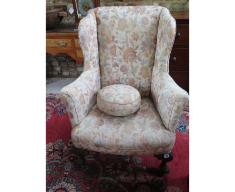 A wingback upholstered armchair on carved cabriole legs