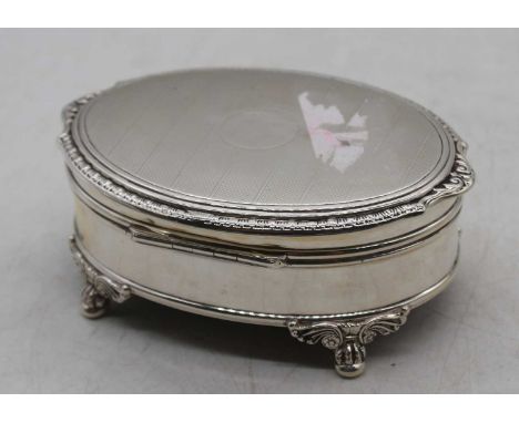 A George VI silver trinket box, of oval form, having a hinged engine turned cover with vacant cartouche and lined interior, r