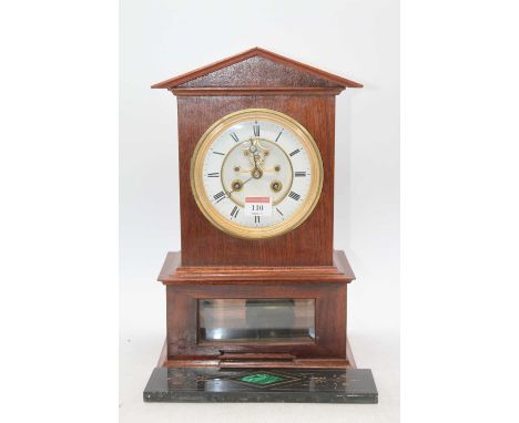 A walnut cased mantel clock, having a circular enamelled chapter ring with Roman numerals, visible anchor escapement and eigh